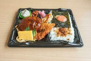 japonés bento conjunto almuerzo caja de hamburguesa bife, algas marinas en arroz, frito pescado y japonés arrollado tortilla foto