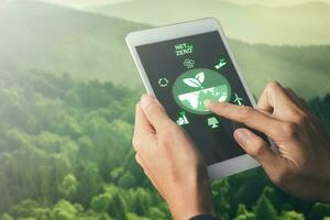 hand holing tablet with net zero target and carbon credit on screen.CO2 emission reduction to stop global warming problem and reduce pollution into atmosphere from big industrial. photo
