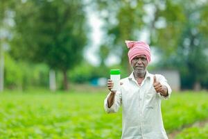 Indian happy farmer holding empty Bottle in hands, happy farmer showing white Bottle photo