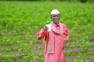 Indian happy farmer holding empty Bottle in hands, happy farmer showing white Bottle photo