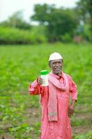 Indian happy farmer holding empty Bottle in hands, happy farmer showing white Bottle photo