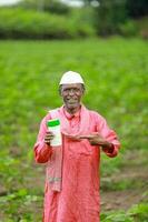 Indian happy farmer holding empty Bottle in hands, happy farmer showing white Bottle photo