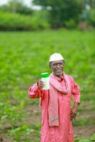 Indian happy farmer holding empty Bottle in hands, happy farmer showing white Bottle photo