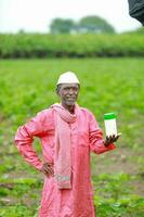 Indian happy farmer holding empty Bottle in hands, happy farmer showing white Bottle photo