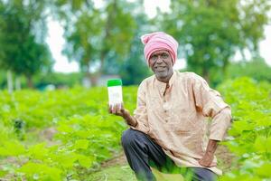 Indian happy farmer holding empty Bottle in hands, happy farmer showing white Bottle photo