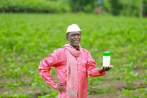 Indian happy farmer holding empty Bottle in hands, happy farmer showing white Bottle photo