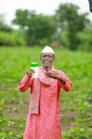 Indian happy farmer holding empty Bottle in hands, happy farmer showing white Bottle photo