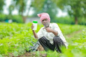 Indian happy farmer holding empty Bottle in hands, happy farmer showing white Bottle photo