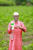 Indian happy farmer holding empty Bottle in hands, happy farmer showing white Bottle photo