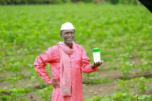 Indian happy farmer holding empty Bottle in hands, happy farmer showing white Bottle photo