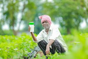 Indian happy farmer holding empty Bottle in hands, happy farmer showing white Bottle photo