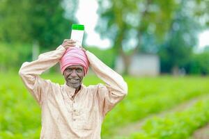 Indian happy farmer holding empty Bottle in hands, happy farmer showing white Bottle photo