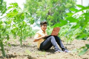 Indian boy studying in farm, holding laptop in hand , poor indian kids photo