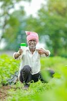 Indian happy farmer holding empty Bottle in hands, happy farmer showing white Bottle photo