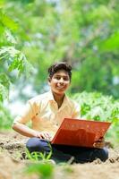 indio chico estudiando en granja, participación ordenador portátil en mano , pobre indio niños foto