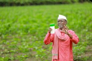 Indian happy farmer holding empty Bottle in hands, happy farmer showing white Bottle photo