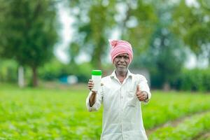 indio contento granjero participación vacío botella en manos, contento granjero demostración blanco botella foto
