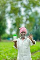 Indian happy farmer holding empty Bottle in hands, happy farmer showing white Bottle photo