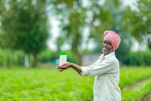 Indian happy farmer holding empty Bottle in hands, happy farmer showing white Bottle photo