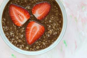 Chocolate oatmeal porridge and strawberry in bowl photo