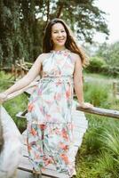 Happy mixed-race Japanese woman in romantic floral maxi dress in park photo