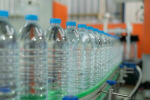 Water factory - Water bottling line for processing and bottling pure mineral water into blue bottles. Selective focus. photo