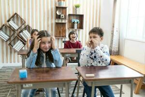 Happy smiling boy and girl school children studying together using tablet device in classroom. Groups of schoolchildren working on task. education concept. photo