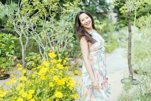 Happy mixed-race Japanese woman in romantic floral maxi dress in summer park photo