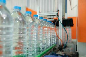 Water factory - Water bottling line for processing and bottling pure mineral water into blue bottles. Selective focus. photo