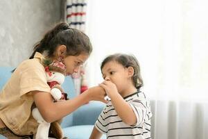 pequeño chico y su más viejo hermana comiendo chocolate a hogar. foto