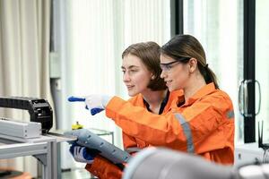 contento joven ingeniero dos hembra automatización máquina ingenieros y inspección controlar robots en un Universidad o fábrica taller. ai robot tecnología innovación tendencia de fabricación en el industria0 foto