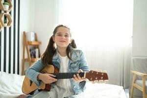 Girl playing guitar relax in the bedroom, enjoy leisure weekend at home. Stress-free concept Cute tween girl photo