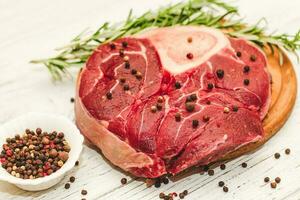 Fresco pedazo de carne grande carne de vaca filete en el hueso Osso Buco con un puntilla de Romero en un negro antecedentes foto