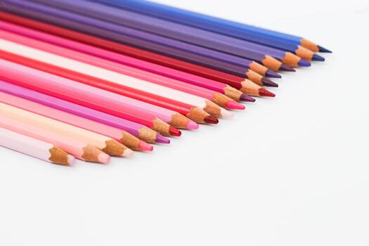 Multi-colored pencils lie on a white table, the violet range of colors photo
