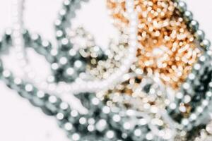 A necklace of gray beads with chain decorations on a white aesthetic background. photo
