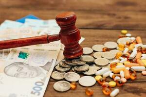 Ukrainian blue yellow flag with judge's gavel, pills and hryvnias on a wooden background photo