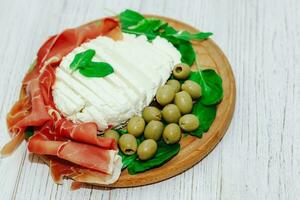 Pieces of dried pork jamon prosciutto with olives and cheese on the board photo