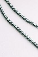 A necklace of gray beads on a white aesthetic background. photo