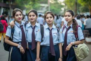 Five beautiful school girls in uniform, possibly from a private school, pose together for a picture. photo