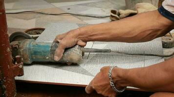 Asian hand cutting floor tiles using hand grinder video