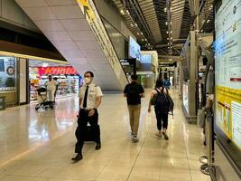 Evening at Suvarnabhumi Airport, Bangkok, on July 7, 2023. A bustling departures corridor nearby a retail store comes alive. photo