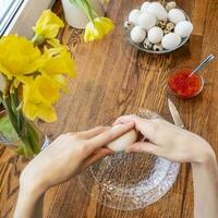 Woman peeling boiled egg on wooden background photo