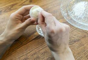 Woman peeling boiled egg on wooden background photo