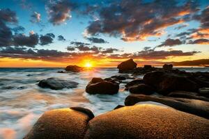 Waves and rocks on beach of sunset photo