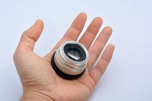 cámara lente en mano en un blanco antecedentes foto
