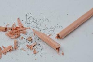 broken pencil writing with a pencil Written word begin again white background photo