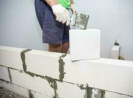 Plastering the wall.Hand holding a spatula with construction mix.Applying putty or tile glue to with lightweight concrete blocks.Plaster the wall with a putty knife.Internal construction photo