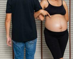 grande embarazada mujer con hombre frente a espalda foto