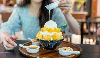 Shaved ice dessert with mango slices. Served with vanilla ice cream and whipped cream. Sweet dessert in Korean style. Local name, Bingsu. photo