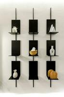 Black shelf hanging on white wall. Concept of storing stuff and keeping it organized with limited tools. photo